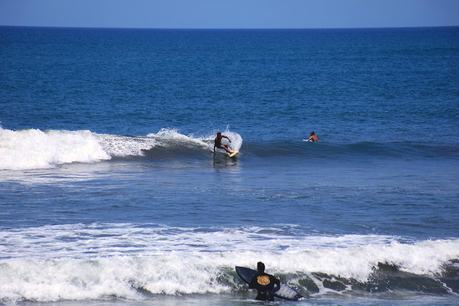 Surfer carving a wave out the back while another paddles out