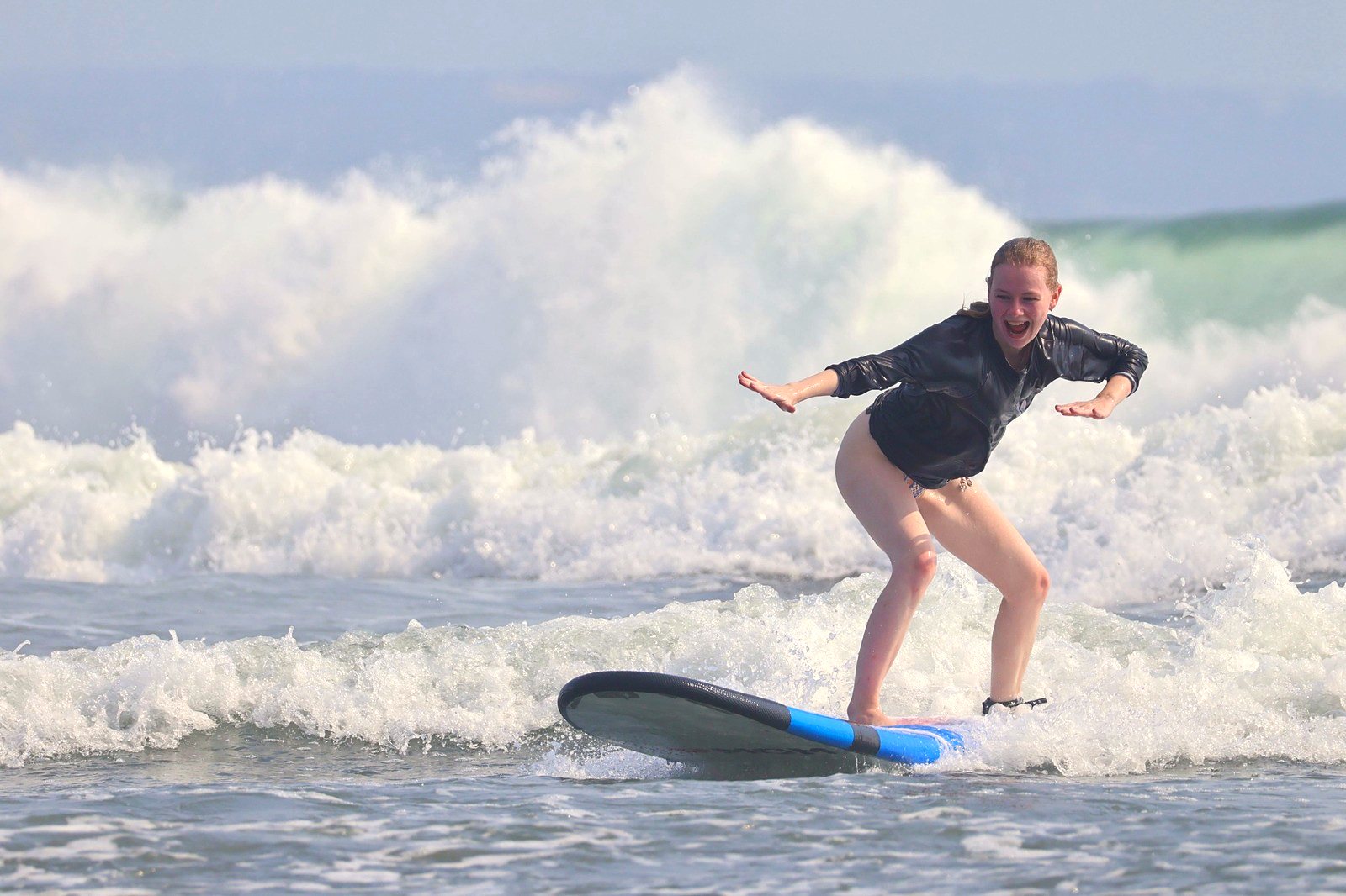 Student laughing as she rides her first wave
