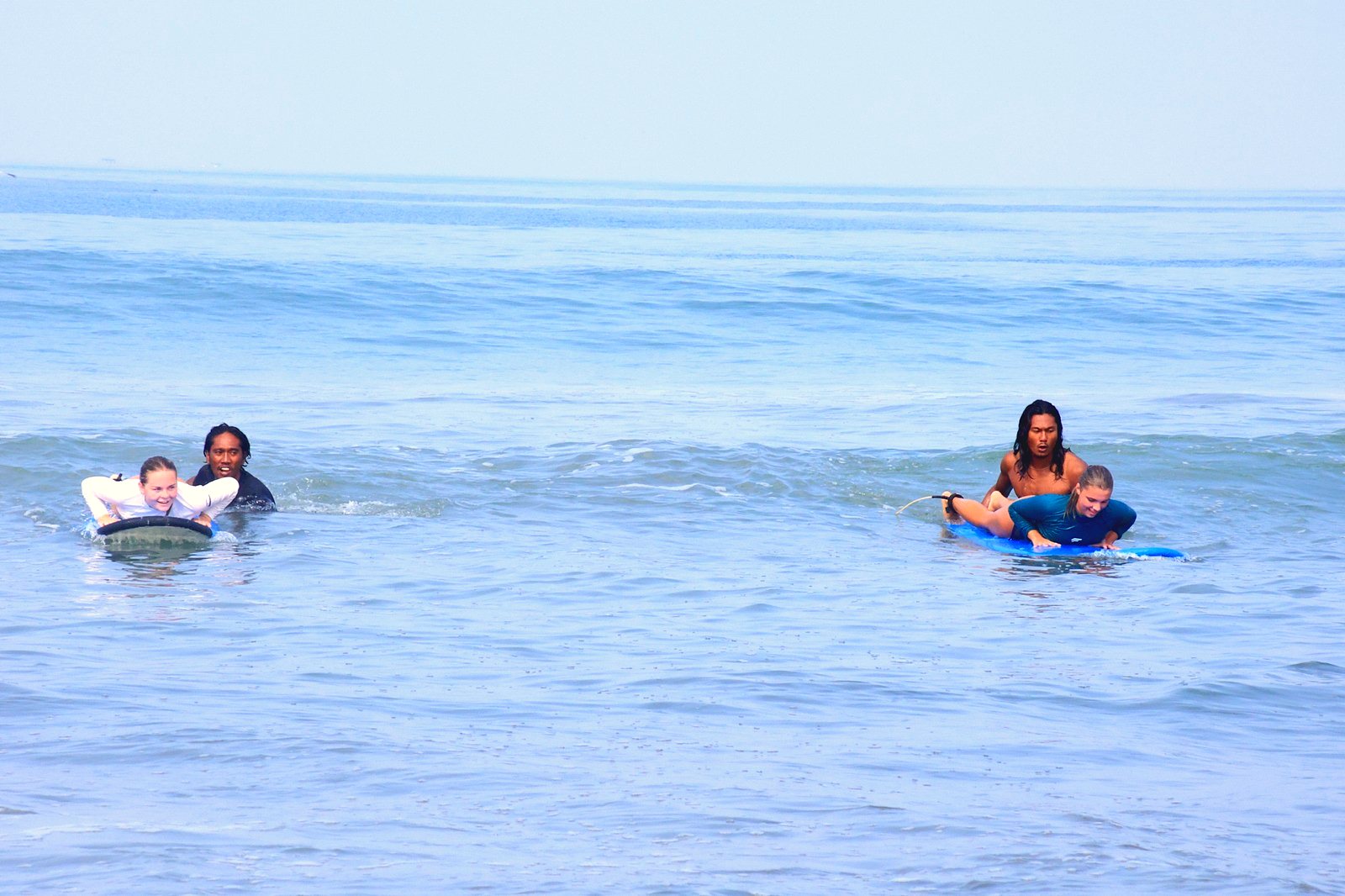 Instructors pushing two students into a wave