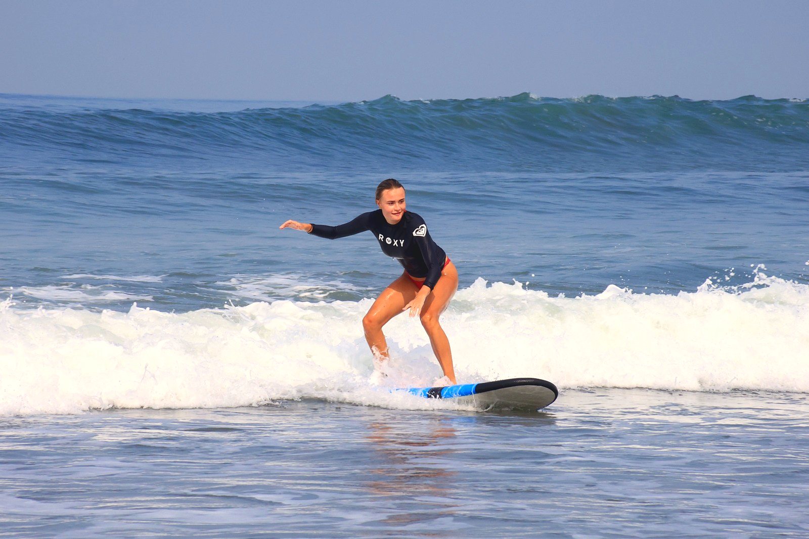 Student riding a wave with arms out for balance