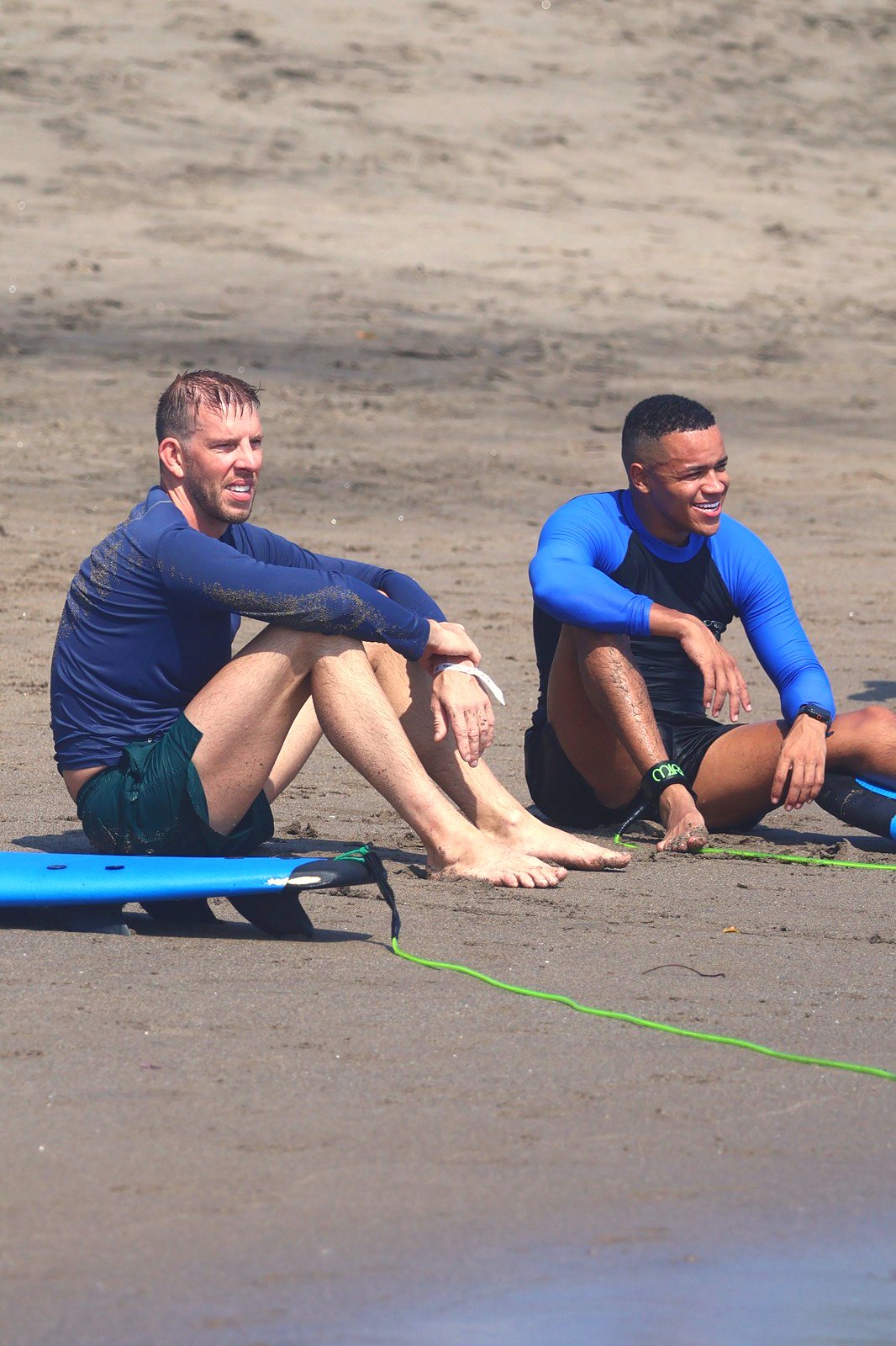 Two students resting on the sand between waves