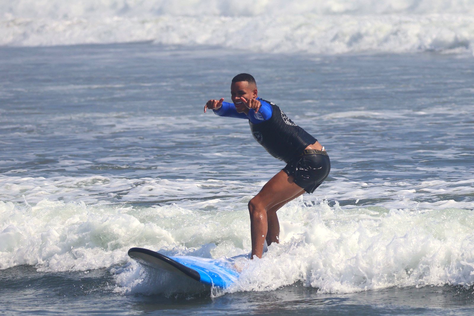 Surfer throwing shakas while riding a wave