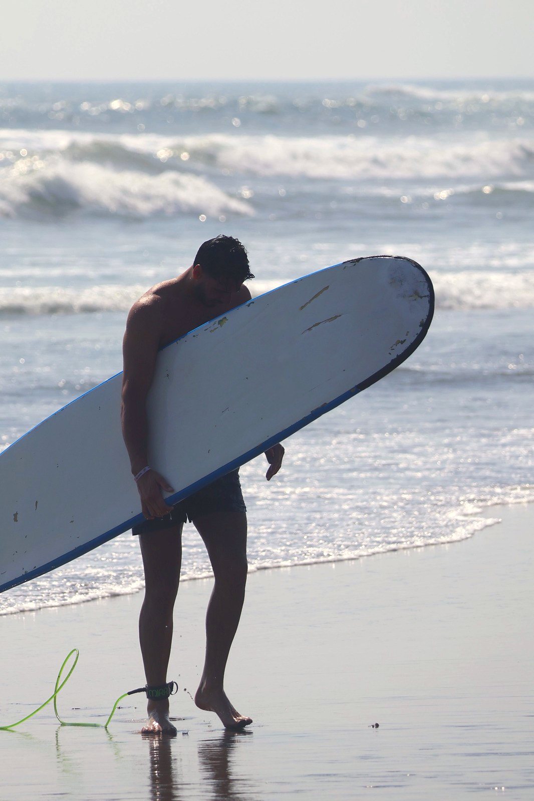 Surfer walking out of the water with his board