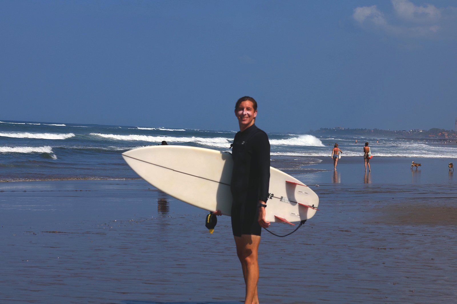 Surfer in a wetsuit holding his shortboard on the beach