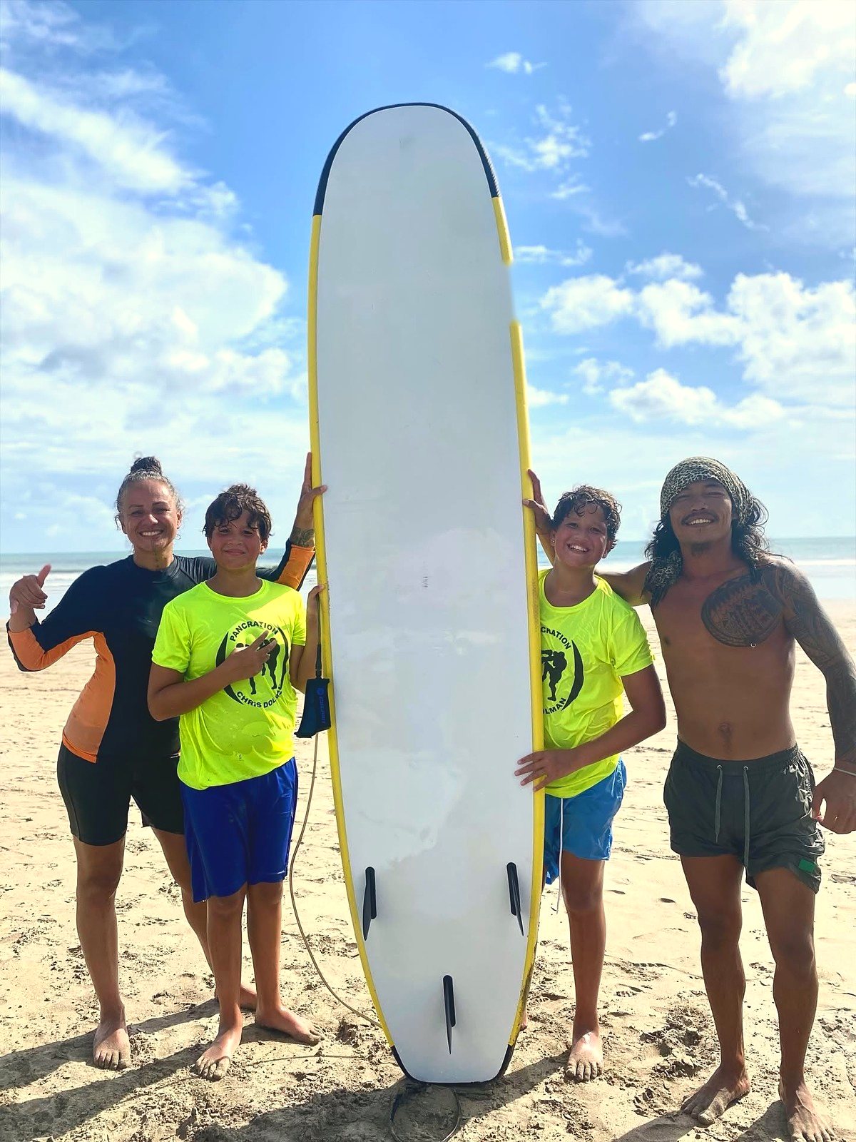 Family and their instructor posing with a surfboard after a lesson