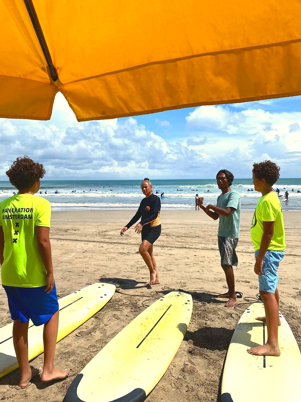 Instructors coaching a family on the sand under a beach umbrella