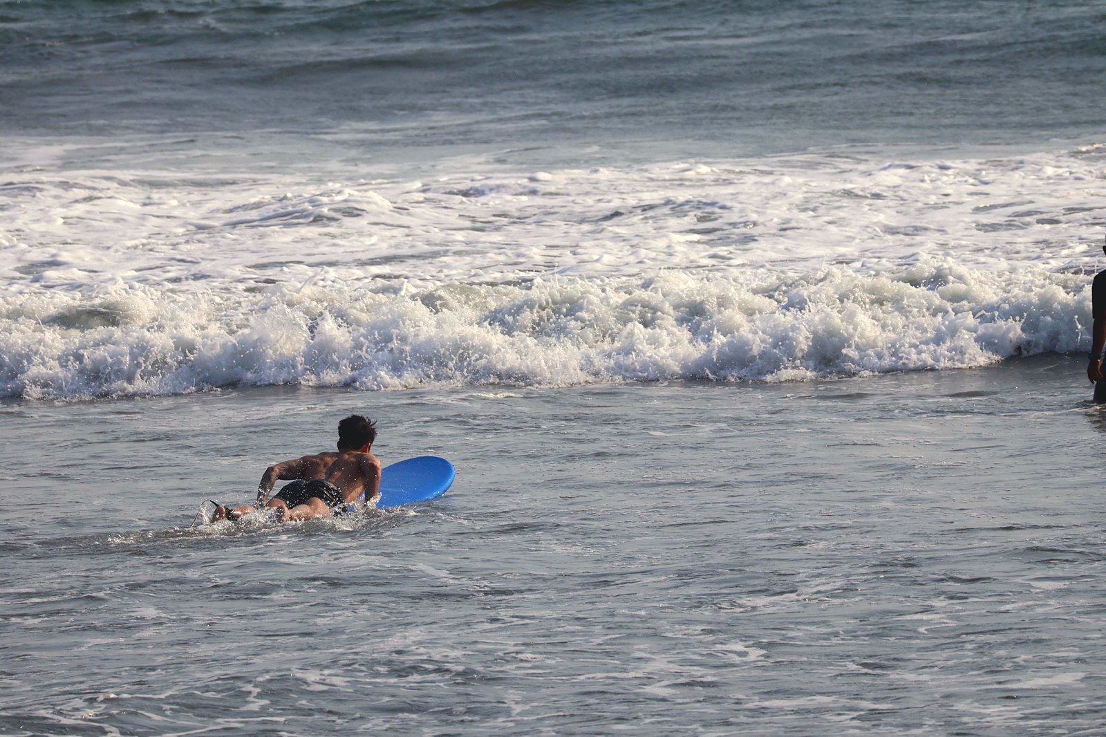 Surfer paddling out toward the breaking waves