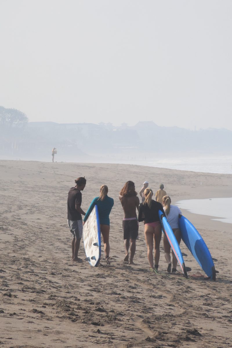 Mika and students carrying boards along a misty beach