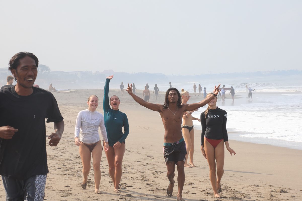 Mika and a group of happy students walking up the beach