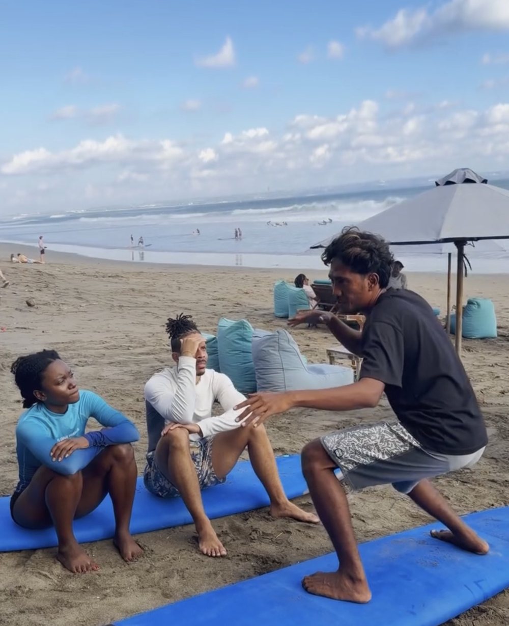 Mika demonstrating the surf stance to two students on the sand