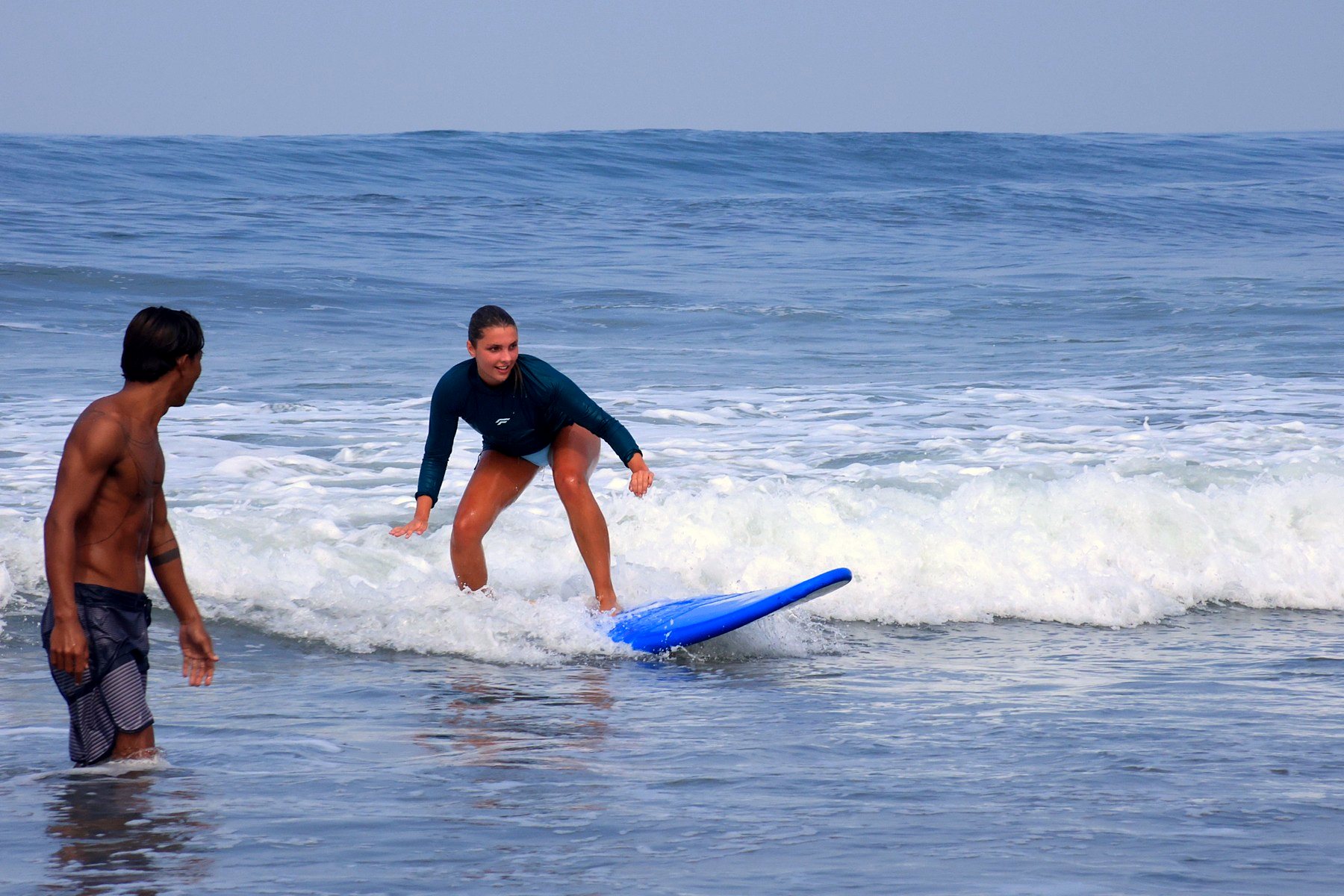 Student standing up on a blue board while her instructor cheers