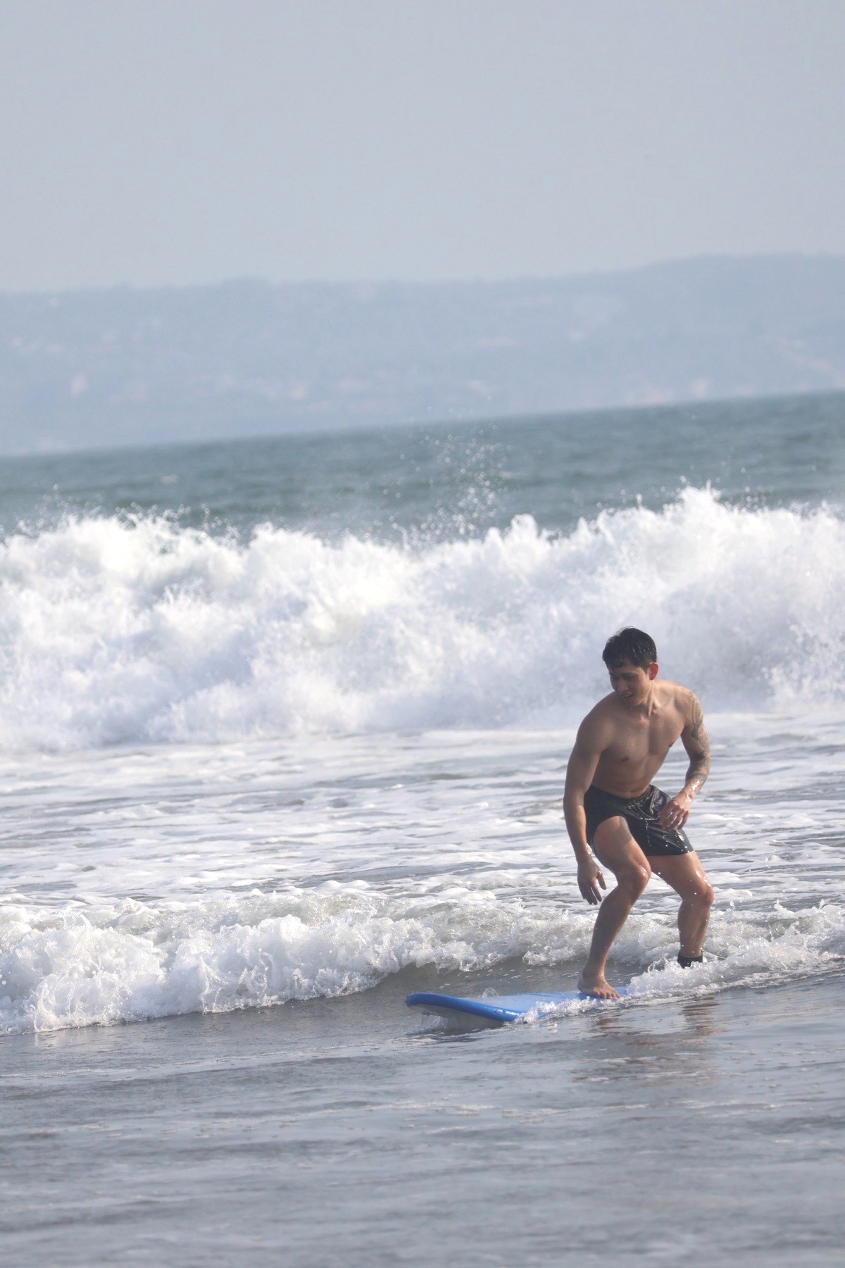 Surfer riding a blue board in front of breaking waves